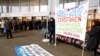 FILE - Protesters display a banner to protest against the financing of the Dakota Access oil pipeline by Swiss banks UBS and Credit Suisse as participants arrive ahead of the annual shareholder meeting of Swiss bank UBS in Basel, Switzerland, May 4, 2017. The banner reads "UBS + Credit Suisse destroy the Standing Rock Native American reserve." 