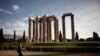 FILE - A tourist makes her way at the archaeological site of the Temple of the Olympian Zeus in Athens, Greece, Nov. 18, 2014. 
