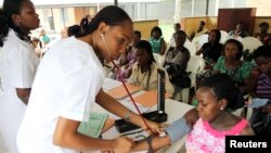 A nurse inspects a pregnant woman outside a ward at a maternity hospital in Obio district in Nigeria's oil city of Port Harcourt, March 24, 2011.