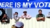Cambodian workers look through a partition of a construction site below a banner which reads "Where is my vote" as supporters of opposition Cambodia National Rescue Party gather in Phnom Penh, Cambodia, Saturday, Sept. 7, 2013.