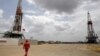 ARCHIVO - Un trabajador de un campo petrolero camina junto a las plataformas de perforación en un pozo de petróleo operado por la petrolera estatal de Venezuela PDVSA, en el rico cinturón petrolero del Orinoco, el 16 de abril de 2015.