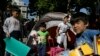 Children carry toys and bags leave from their family's tent at Victoria square, where hundreds migrants and refugees stay temporarily before trying to continue their trip to more prosperous northern European countries, in Athens, Oct. 1, 2015. 