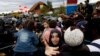Refugees crowd in front of a line of police officers to cross the border from Croatia to the Slovenian village Rigonce at the border station in Harmica, Croatia, Sunday, Sept. 20, 2015.