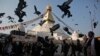Burung merpati beterbangan di Stupa Boudhanath yang baru dibuka lagi untuk publik setelah restorasi pasca gempa di Kathmandu, Nepal (22/11). (AP/Niranjan Shrestha)