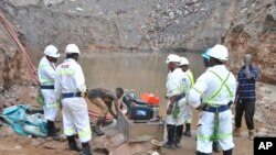 Sejumlah penambang beserta di tim evakuasi tampak berada di lokasi pertambangan di Chingola, Zambia, pada 2 Desember 2023. Mereka berupaya mengevakuasi sekitar 30 penambang yang terperangkap akibat longsor yang melanda daerah tersebut. (Foto: AP)