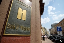 Orang-orang berjalan melewati kantor pusat Bank Pertanian Rusia di pusat kota Moskow, Rusia, pada Rabu, 30 Juli 2014. (Foto: AP)
