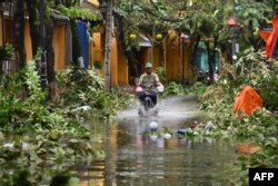 Seorang pria mengendarai sepeda motor di jalan yang tergenang banjir yang dipicu oleh topan Noru di kota Hoi An, provinsi Quang Nam pada 28 September 2022. (Foto oleh Nhac NGUYEN / AFP)