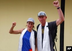 FILE- Hilaree Nelson dari Telluride, Colorado (kiri) dan James Morrison dari Tahoe, California, mengacungkan tinju saat pasangan itu tiba di Kathmandu, Nepal, 4 Oktober 2018. Tim penyelamat dengan helikopter sedang mencari Nelson, pendaki gunung ski AS yang terkenal, di gunung tertinggi kedelapan di dunia, Selasa (27/9), sehari setelah dia jatuh dari gunung di dekat puncak. (AP/Niranjan Shrestha, File)