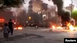 Potongan gambar yang diambil dari video yang beredar di media sosial menunjukkan seorang pengendara motor mengendarai motornya melalui kobaran api dalam protes terkait kematian Mahsa Amini di Javanrud, Iran, pada 8 Oktober 2022. (Foto: Reuters)