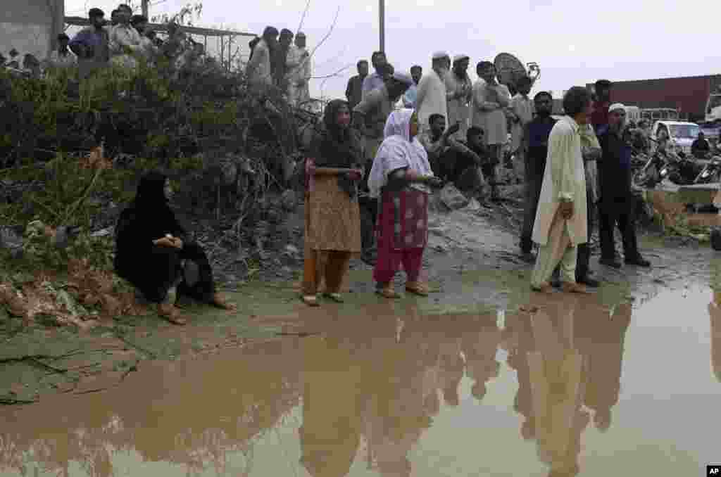 People gather near the site of burnt garment factory in Karachi, Pakistan, September 12, 2012.