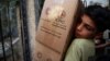 A boy unloads aid parcels in the rebel-held besieged town of Zamalka, in the Damascus suburbs, Syria, June 29, 2016. 