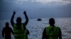 FILE - Volunteers guide an overcrowded dingy with refugees and migrants as it is approaches the beach after crossing part of the Aegean sea from Turkey to the Greek island of Lesbos, Feb. 19, 2016.