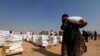 FILE - A displaced woman, who fled from Mosul due to Islamic State violence, carries food in Khazer refugee camp, east of Mosul, Iraq November 7, 2016. 