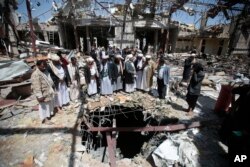 FILE- In this Oct. 13, 2016 file photo, members of the Higher Council for Civilian Community Organization inspect a destroyed funeral hall as they protest against a deadly Saudi-led airstrike in Sana'a, Yemen.