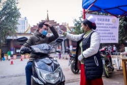 တရုတ်-မြန်မာနယ်စပ်မှ မြန်မာနိုင်ငံတွင်း ဝင်ရောက်လာသူအား ကျန်းမာရေးစစ်ဆေးနေသည့် တာဝန်ရှိသူတဦး။ (ဇန်နဝါရီ ၃၁၊ ၂၀၂၀