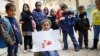 FILE - Syrian refugee Tesnim Faydo, 8, shows her drawing of a mother crying for her wounded daughter, as she is surrounded by her friends in Yayladagi refugee camp in Hatay province near the Turkish-Syrian border, Turkey, Dec. 16, 2015.