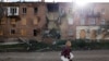 Seorang perempuan berjalan melewati sebuah bangunan yang rusak akibat serangan rudal, saat invasi Rusia ke Ukraina berlanjut, di wilayah Donbas timur Bakhmut, Ukraina, 1 November 2022. (REUTERS/Clodagh Kilcoyne)