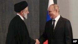 Presiden Rusia Vladimir Putin, kanan, dan Presiden Iran Ebrahim Raisi berjabat tangan saat pertemuan mereka di sela-sela KTT Organisasi Kerja Sama Shanghai (SCO) di Samarkand, Uzbekistan, Kamis, 15 September 2022. (Foto: via AP)