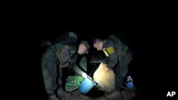 Tim anti-narkoba kepolisian Kolombia memeriksa zat kimia yang digunakan dalam produksi koka di sebuah laboratorium di kawasan terpencil di Orito, Putumayo, Kolombia, pada 9 April 2022. (Foto: AP/Fernando Vergara)