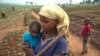 FILE - A woman and her child, who fled from rebel attacks, stand in a field, in Tshikapa, Kasai region, Democratic Republic of Congo, July 27, 2017.