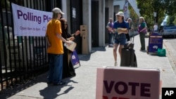 Para relawan berbicara dengan para pemilih di tempat pemungutan suara di Redfern pada pelaksanaan referendum mengenai hak-hak suara masyarakat adat, di Sydney, Australia, Sabtu, 14 Oktober 2023. (Foto: Rick Rycroft/AP Photo)