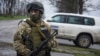FILE - A Ukrainian soldier guards OSCE observers near the village of Shyrokyne, eastern Ukraine, April 19, 2015. 