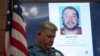 Seorang petugas polisi berdiri di samping layar yang menampilkan gambar tersangka penembak di Balai Kota di Lewiston, Maine, AS 27 Oktober 2023. (Foto: REUTERS/Kevin Lamarque)