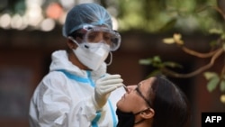 A health worker collects a swab sample from a woman at a Covid-19 coronavirus screening site in New Delhi on October 29, 2020. - India on October 29 passed eight million coronavirus cases, with the world's second-worst-hit country bracing for a possible s