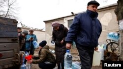 Мешканці містечка Часів Яр, що поблизу Бахмута, наповнюють пляшки свіжою питною водою, яку привезли в район лінії фронту після ураження критичної цивільної інфраструктури під час нападу Росії на Україну. Архівне фото 16 березня 2023 року. REUTERS/Віолета Сантос Моура/Фото з файлу