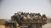 FILE - Migrants sit on their belongings in the back of a truck as it is driven through a dusty road in the desert town of Agadez, Niger, headed for Libya, May 25, 2015. 