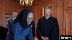 Hakim Ketanji Brown Jackson menandatangani sumpahnya sebagai Hakim Mahkamah Agung, disaksikan Hakim Mahkamah Agung John Roberts dalam acara pelantikan di Washington, pada 30 Juni 2022. (Foto: Collection of the Supreme Court of the United States/Handout via Reuters)