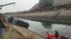 Warga berdiri di sepanjang kanal menyaksikan tim penyelamat melakukan pencarian korban bus yang jatuh ke kanal, di distrik Sidhi, negara bagian Madhya Pradesh, 16 Februari 2021. (Foto: Uma Shankar MISHRA / AFP).