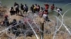 ARCHIVO - Migrantes aguardan detrás de los alambres de púas tras cruzar el Río Grande hacia Estados Unidos en Eagle Pass, Texas, EEUU, el 28 de septiembre de 2023.